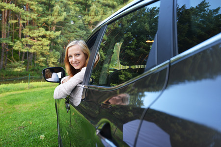 Smiling woman sit in car.car stands on green gladeの写真素材