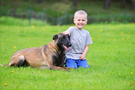 little boy playing with dog on grassの写真素材