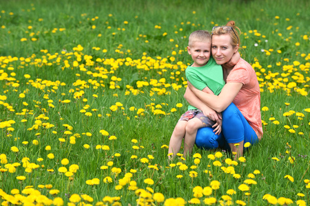 Beautiful young mother with her son playing on grass . summer dayの写真素材