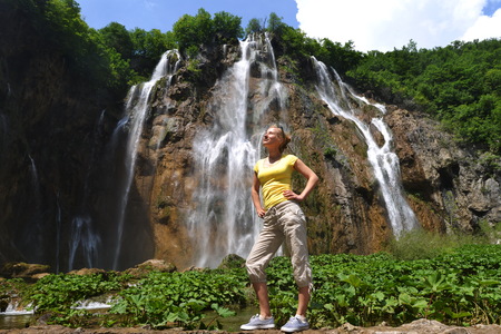 young woman near beautiful waterfalls on slopes of mountainsの写真素材