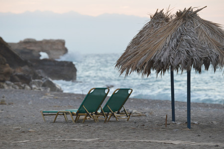 Beach chairs with straw umbrellas on sea beachの写真素材