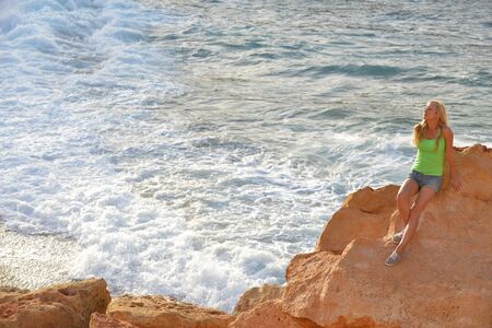 young woman among  rocks near blue seaの写真素材