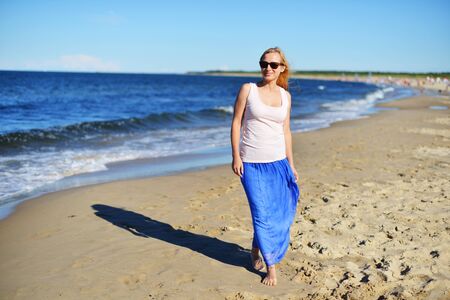 Young woman walking on sand beachの写真素材