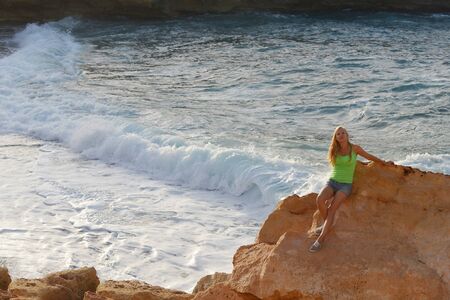 young woman among  rocks near blue seaの写真素材