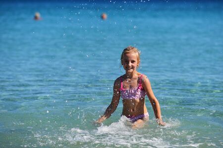 cute girl playing on shore of blue seaの写真素材