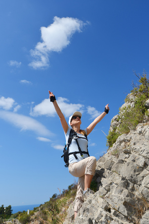 woman climbs mountainside to topの写真素材