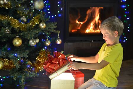 little boy looks gifts near Christmas treeの写真素材