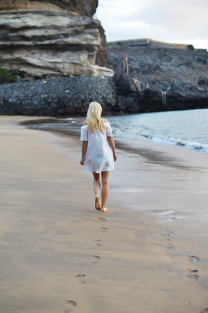 Evening landscape. pretty woman is walking along seashoreの写真素材