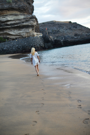 evening landscape. pretty woman is walking along  seashoreの写真素材