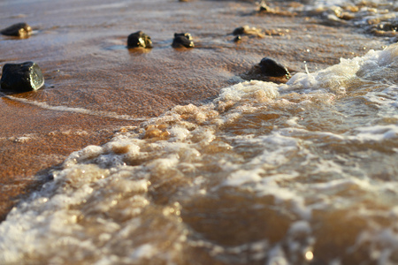 sea beach. Stones on sand are washed by sea wavesの写真素材