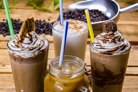 Four cold coffee drinks with roasted coffee beans in the backgroundの写真素材