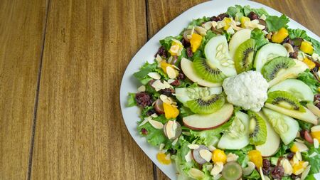 Fresh salad with kiwi, apple, blueberries, peach, lettuce, cucumber, grapes, almonds and cheeseの写真素材