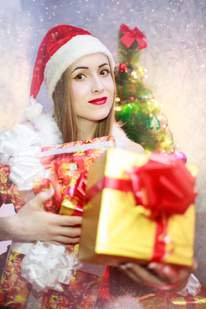 Sexy blonde girl with gift box smiling and wearing Santa Claus clothes.の写真素材