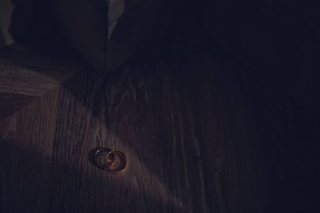 The groom's rings on a dark background illuminated by a ray of sunshine