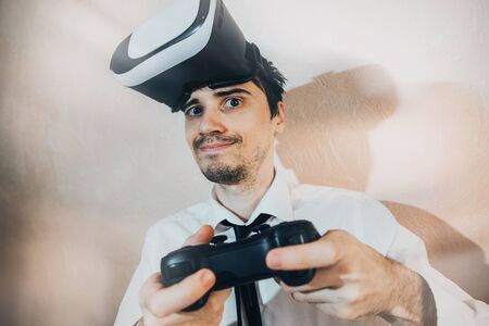 the emotions of a man playing with the joystick in a vr game, dressed in a white shirt with a tie