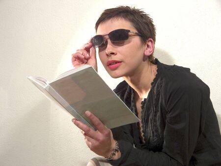 Woman with sunglassess is reading bookの写真素材