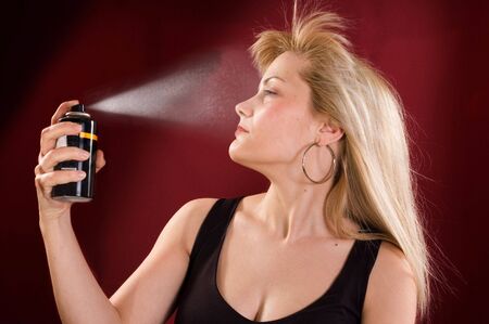 Woman's portrait with deodorant spray on her hairの写真素材