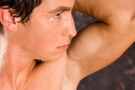 Sweaty bodybuilder training with dumbbell with droplet on his bodyの写真素材