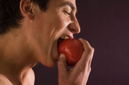 Young man eating red appleの写真素材