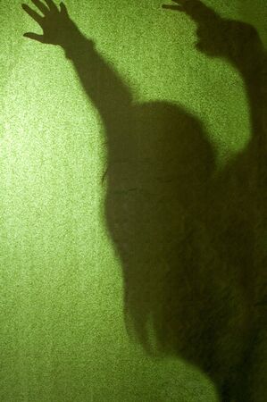 Silhouette of naked girl posing behind green backgroundsの写真素材