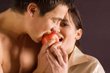 Young happy and beautiful couple eating appleの写真素材