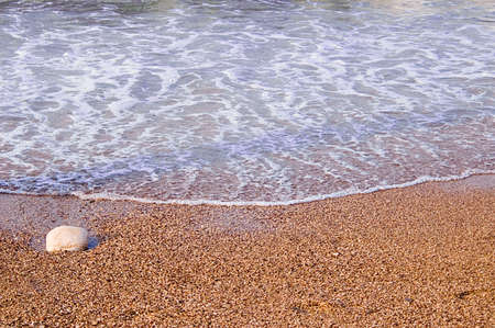 Sand beach with one stone and wavesの写真素材