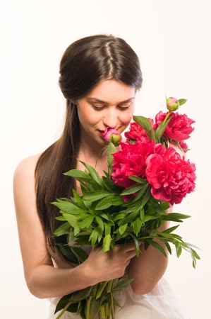 Beautiful cute woman smelling a red flowersの写真素材