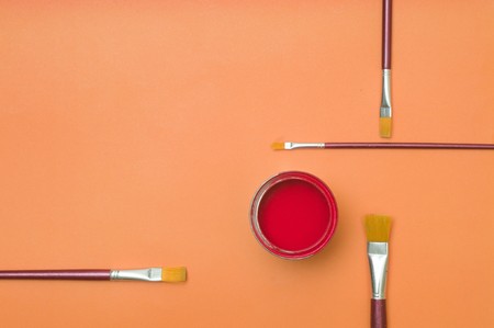 Red colors paint in tin with paint brushes on orange backgroundsの写真素材