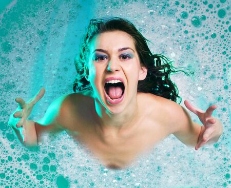 Furious woman gesturing  her hands and crying in soap bubbleの写真素材