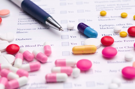 Pen, pills variety and medical certificate form that requires to fill out his required information. Focus on blue capsule の写真素材