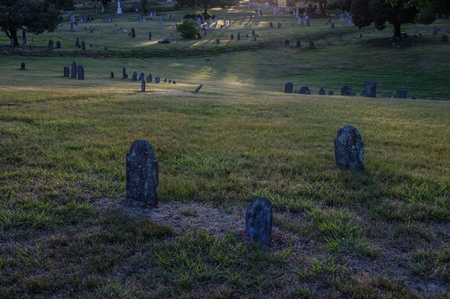 Three grave stones in a churchyard in early evening light