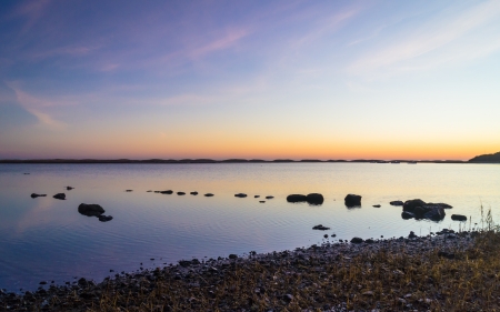 Line of rocks stretching out into a calm inlet at sunrise の写真素材