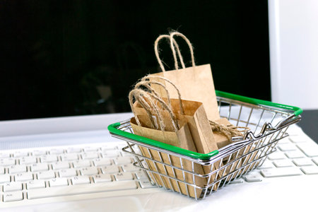 Shopping cart with groceries on laptop keyboard on white background, selective focus. Ordering products online, Copy spaceの写真素材
