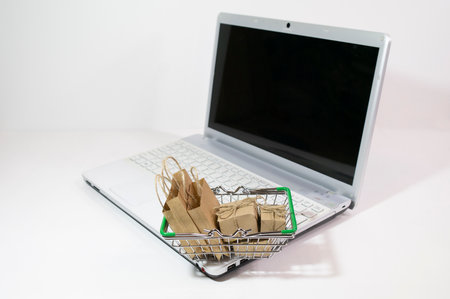 Shopping cart with groceries on laptop keyboard on white background, selective focus. Ordering products online, Copy spaceの写真素材