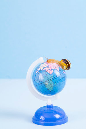 Travel concept, snail crawling across the globe, copy space. High quality photo