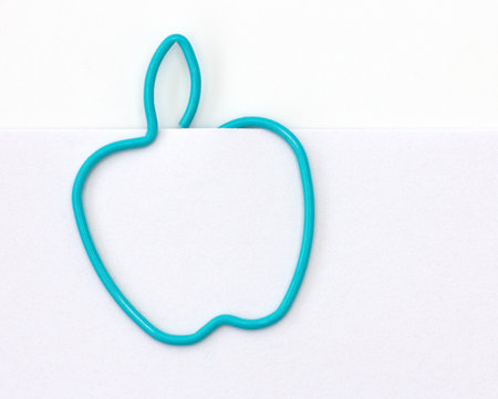 Paper clip in the form of apple on a sheet of paper の写真素材