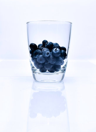 Blueberries in drinking glass with white background.の写真素材