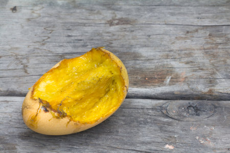 rotten ripe mango bitten by insect or squirrels on the wooden table.