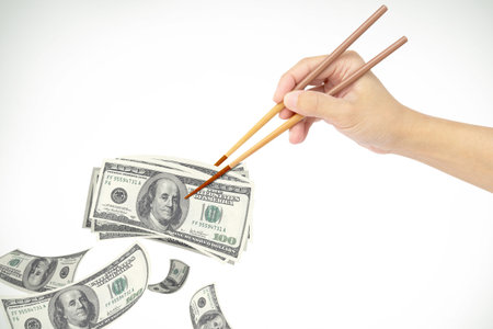 hand clipping dollar money with chopstickの写真素材