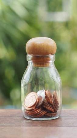 Half of bottle of  coin  on wood tableの写真素材