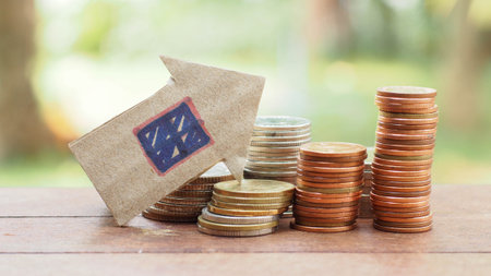 Stack of coin and paper house on the wood tableの写真素材