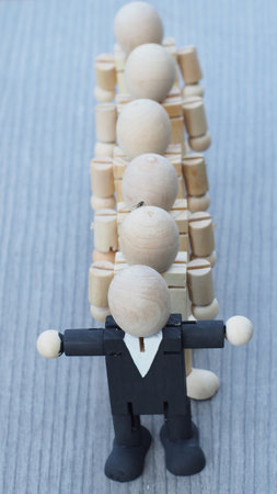 wooden doll of businessman as teamwork with the leader on the front, business leadership and teamwork conceptの写真素材