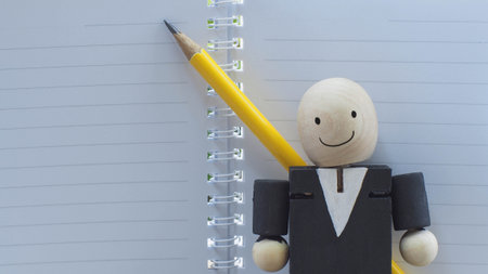 wooden doll of businessman thinking an idea with his pencil and notebook paper, business conceptの写真素材