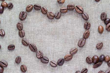 Heart of coffee beans on a linen backgroundの写真素材