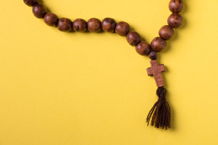 Wooden rosary and cross on yellow background.の写真素材