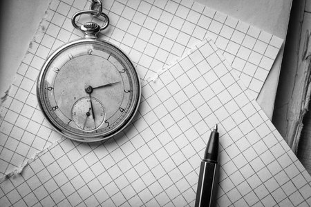 Old clock, pages of paper in a cage, a pen on a wise book. Concept of education. Black and white photographyの写真素材
