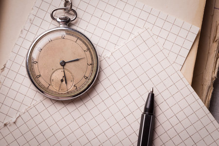 Old clock, pages of paper in a cage, a pen on a wise book. Concept of education.の写真素材