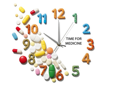 Time to take medicine. Clock made of colorful pills on white backgroundの素材