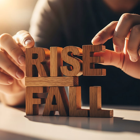 Person building the word rise over fall with wooden block letterの素材