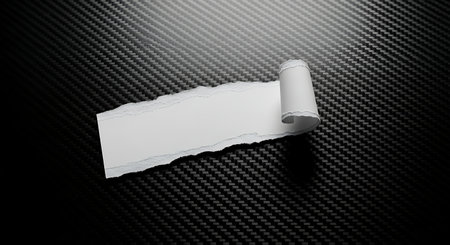 Torn white paper strip with rolled edge on black carbon fiberの素材